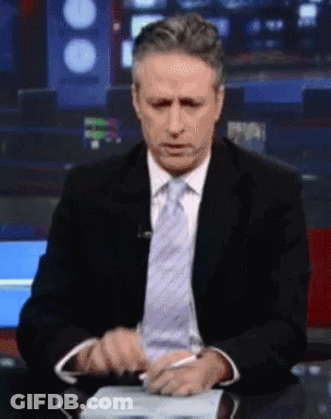 A Man In A Suit And Tie Sitting At A Desk GIF