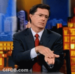 A Man In A Suit And Tie Sitting At A Table GIF