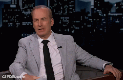 A Man In A Suit And Tie Sitting In A Chair GIF