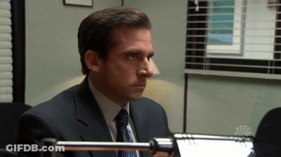 A Man In A Suit And Tie Sitting In Front Of A Nbc Logo GIF