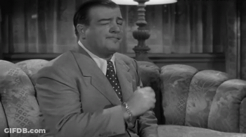 A Man In A Suit And Tie Sitting On A Couch GIF