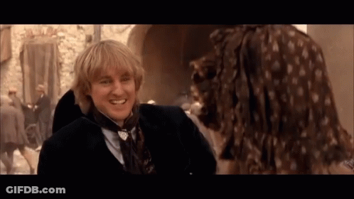 A Man In A Suit And Tie Smiles At A Woman In A Dress GIF