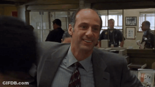 A Man In A Suit And Tie Smiles In A Room GIF