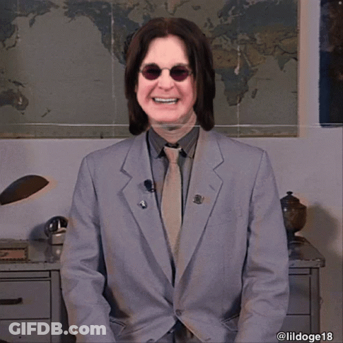 A Man In A Suit And Tie Smiles In Front Of A World Map GIF