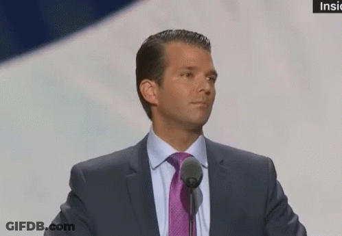 A Man In A Suit And Tie Speaking Into A Microphone . GIF