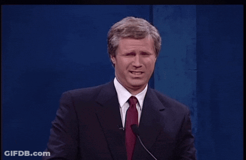 A Man In A Suit And Tie Stands At A Podium GIF