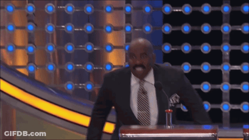 A Man In A Suit And Tie Stands At A Podium With A Microphone GIF