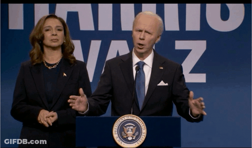 A Man In A Suit And Tie Stands At A Podium With A Woman Behind Him In Front Of A Sign That Says Vaz GIF
