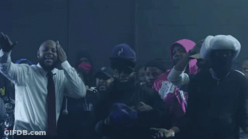 A Man In A Suit And Tie Stands In A Crowd GIF