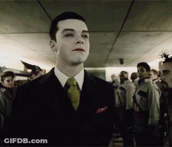 A Man In A Suit And Tie Stands In A Crowd Of People GIF
