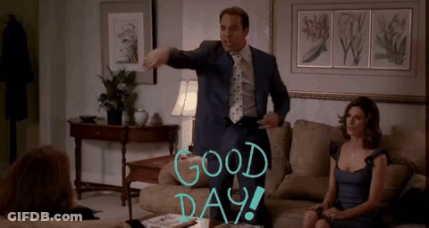 A Man In A Suit And Tie Stands In A Living Room With The Words Good Day Written On The Wall GIF