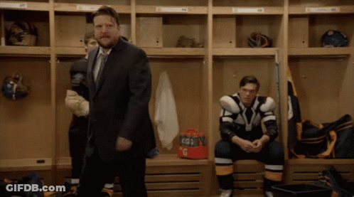 A Man In A Suit And Tie Stands In A Locker Room GIF