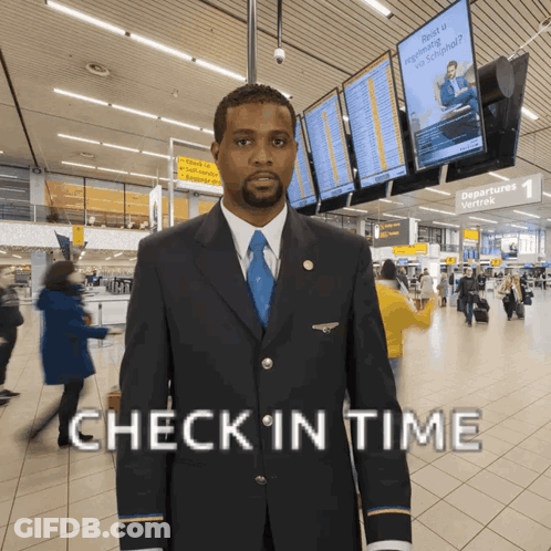 A Man In A Suit And Tie Stands In An Airport With The Words Check In Time Above Him GIF