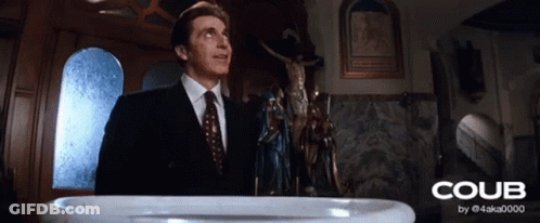 A Man In A Suit And Tie Stands In Front Of A Baptismal Font That Says Coub On It GIF