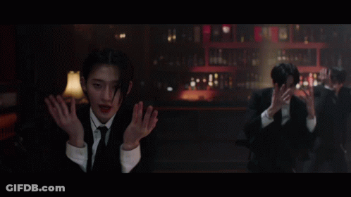 A Man In A Suit And Tie Stands In Front Of A Bar GIF