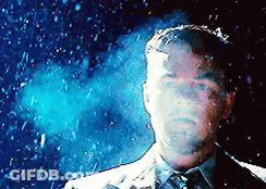 A Man In A Suit And Tie Stands In Front Of A Blue Background GIF