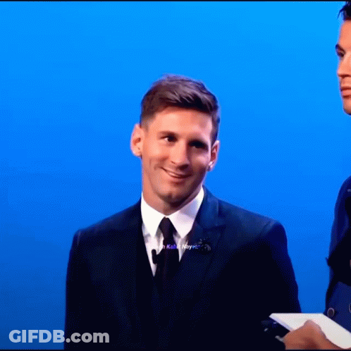 A Man In A Suit And Tie Stands In Front Of A Blue Wall GIF