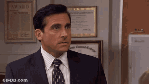 A Man In A Suit And Tie Stands In Front Of A Bulletin Board With A Certificate Of Agreement On It GIF