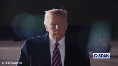 A Man In A Suit And Tie Stands In Front Of A C-Span Sign GIF