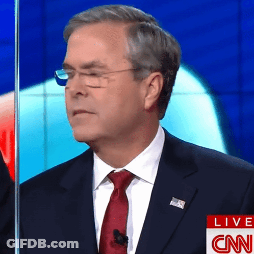 A Man In A Suit And Tie Stands In Front Of A Cnn Live Screen GIF