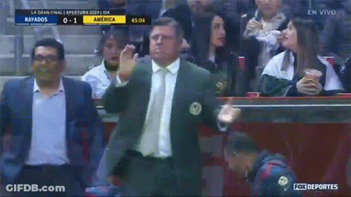 A Man In A Suit And Tie Stands In Front Of A Crowd Watching A Soccer Game Between Rayados And America GIF