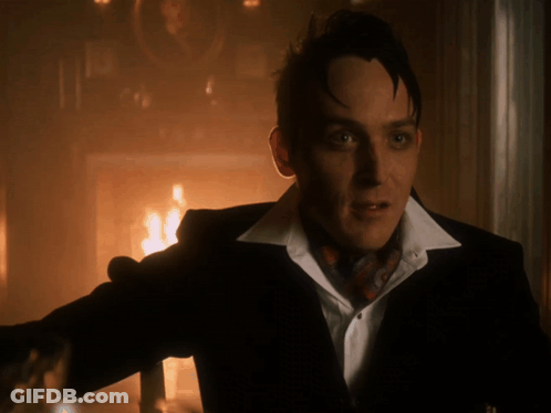 A Man In A Suit And Tie Stands In Front Of A Fire GIF