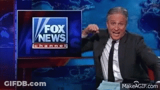 A Man In A Suit And Tie Stands In Front Of A Fox News Channel Sign GIF
