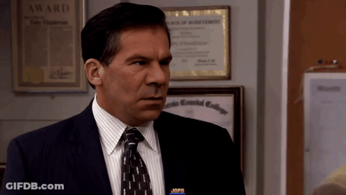 A Man In A Suit And Tie Stands In Front Of A Framed Award GIF