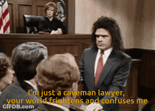 A Man In A Suit And Tie Stands In Front Of A Group Of People And Says I 'M Just A Caveman GIF