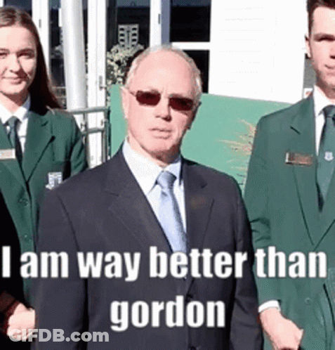 A Man In A Suit And Tie Stands In Front Of A Group Of People With The Caption I Am Way Better Than Gordon . GIF