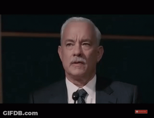 A Man In A Suit And Tie Stands In Front Of A Microphone And A Youtube Subscribe Button GIF