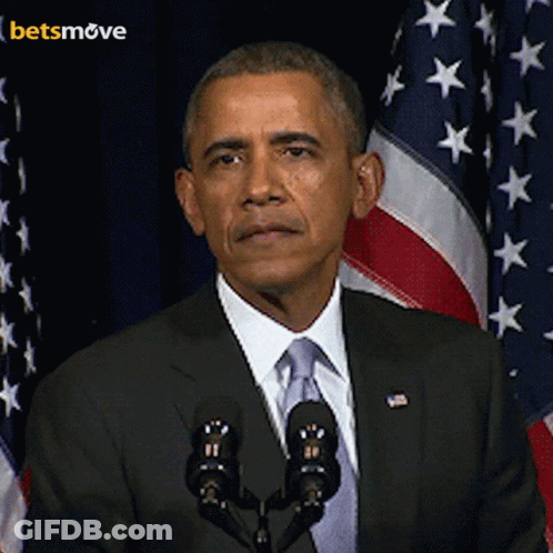 A Man In A Suit And Tie Stands In Front Of A Microphone With A Betsmove Logo In The Background GIF