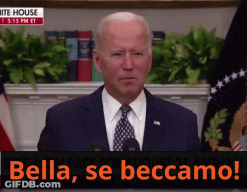A Man In A Suit And Tie Stands In Front Of A Microphone With The Words Bella Se Beccamo On The Bottom GIF