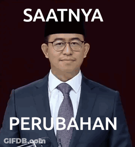 A Man In A Suit And Tie Stands In Front Of A Microphone With The Words Saatnya Perubahan Written Below Him GIF