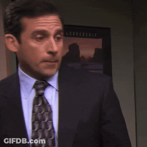 A Man In A Suit And Tie Stands In Front Of A Picture That Says ' Sunset ' On It GIF