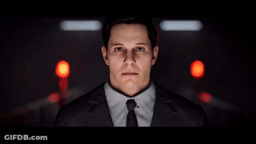 A Man In A Suit And Tie Stands In Front Of A Red Light GIF