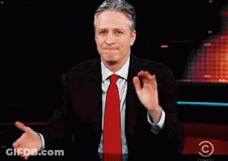 A Man In A Suit And Tie Stands In Front Of A Screen That Says Comedy Central GIF