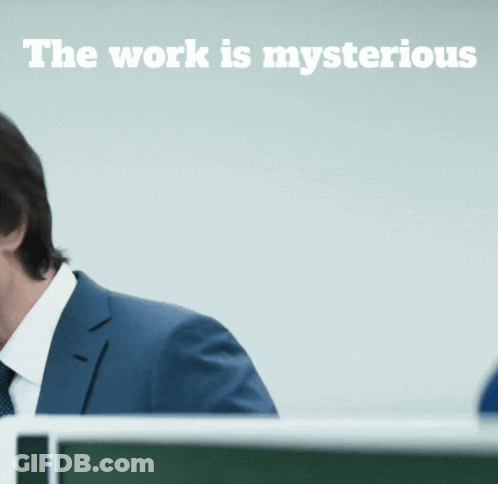 A Man In A Suit And Tie Stands In Front Of A Sign That Says The Work Is Mysterious GIF