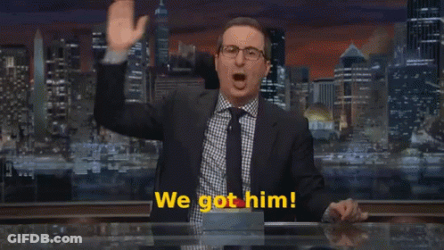 A Man In A Suit And Tie Stands In Front Of A Sign That Says We Come GIF