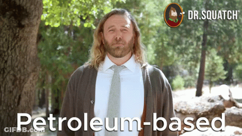 A Man In A Suit And Tie Stands In Front Of A Tree With The Words Petroleum-Based On The Bottom GIF