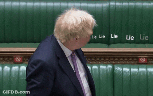 A Man In A Suit And Tie Stands In Front Of A Wall That Says Lie Lie Lie Lie Lie GIF