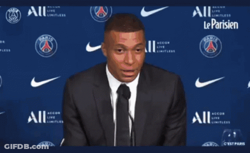 A Man In A Suit And Tie Stands In Front Of A Wall That Says Paris GIF