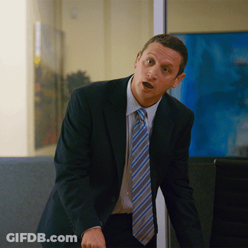A Man In A Suit And Tie Stands In Front Of A Window GIF