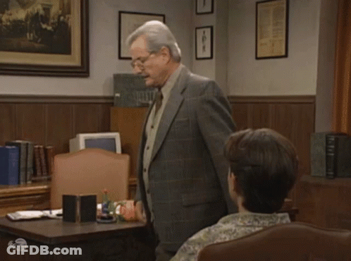 A Man In A Suit And Tie Stands In Front Of A Woman In A Chair With The Words Let Me Show You My Big GIF