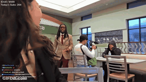 A Man In A Suit And Tie Stands In Front Of A Woman In A Restaurant With Today 'S Subs At 264 GIF