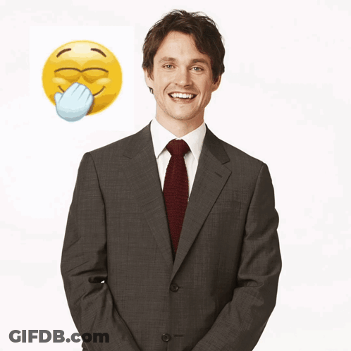 A Man In A Suit And Tie Stands In Front Of A Yellow Smiley Face GIF