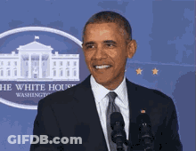 A Man In A Suit And Tie Stands In Front Of Microphones In Front Of The White House GIF