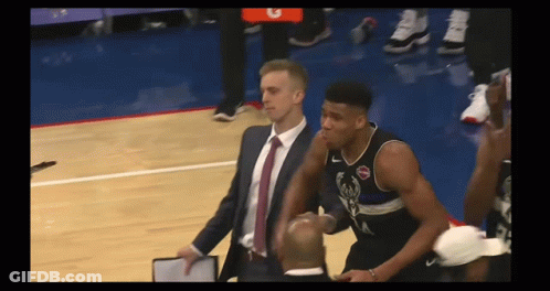 A Man In A Suit And Tie Stands Next To A Basketball Player Wearing A Jersey With The Letter A On It GIF