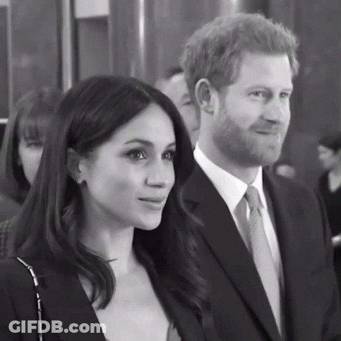 A Man In A Suit And Tie Stands Next To A Woman GIF