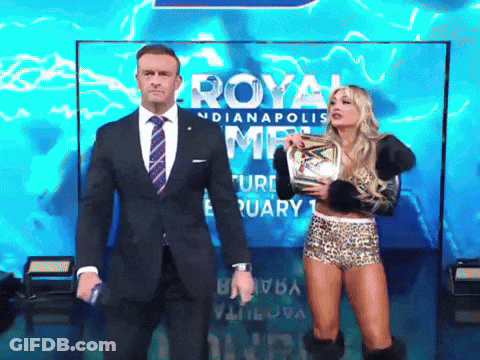 A Man In A Suit And Tie Stands Next To A Woman Holding A Trophy In Front Of A Sign That Says Royal GIF